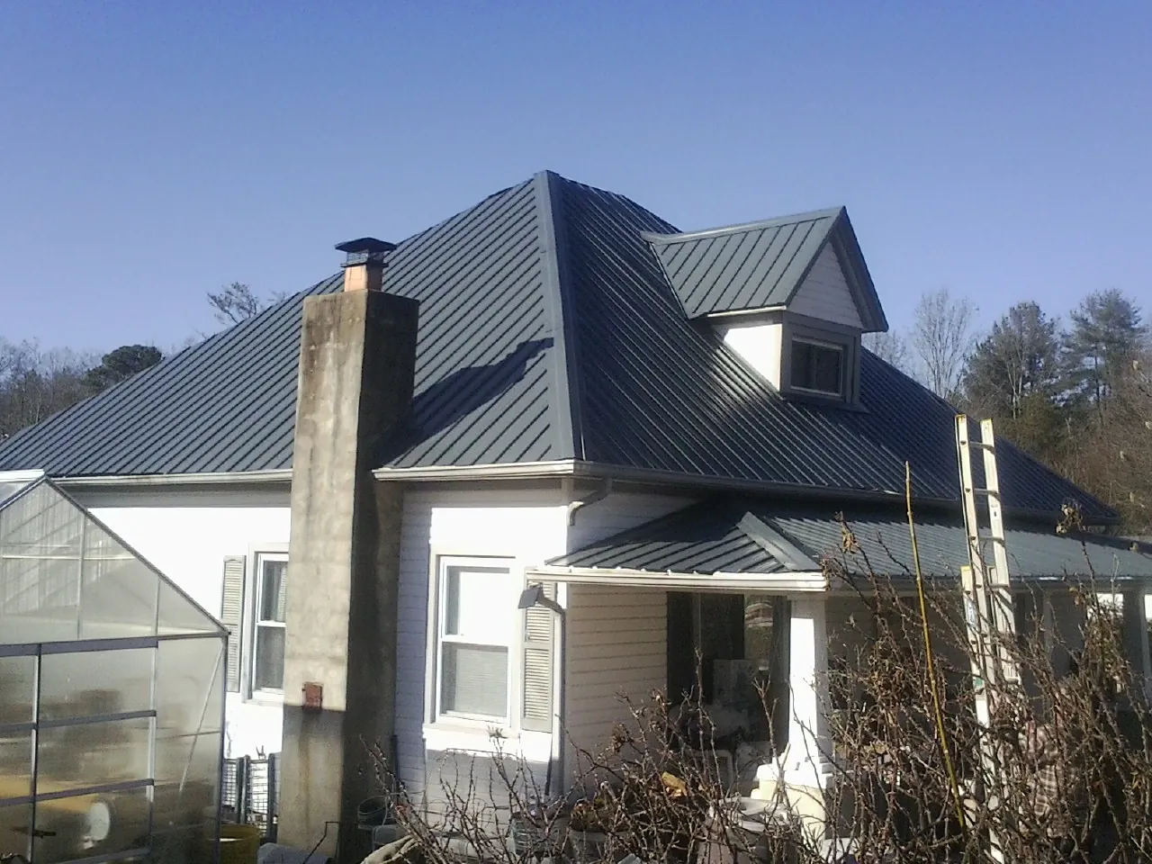 Dark blue standing seam metal roof on a white farmhouse with dormer — Slate & Tile Roof Repair by Roofing Brothers in Crooksville