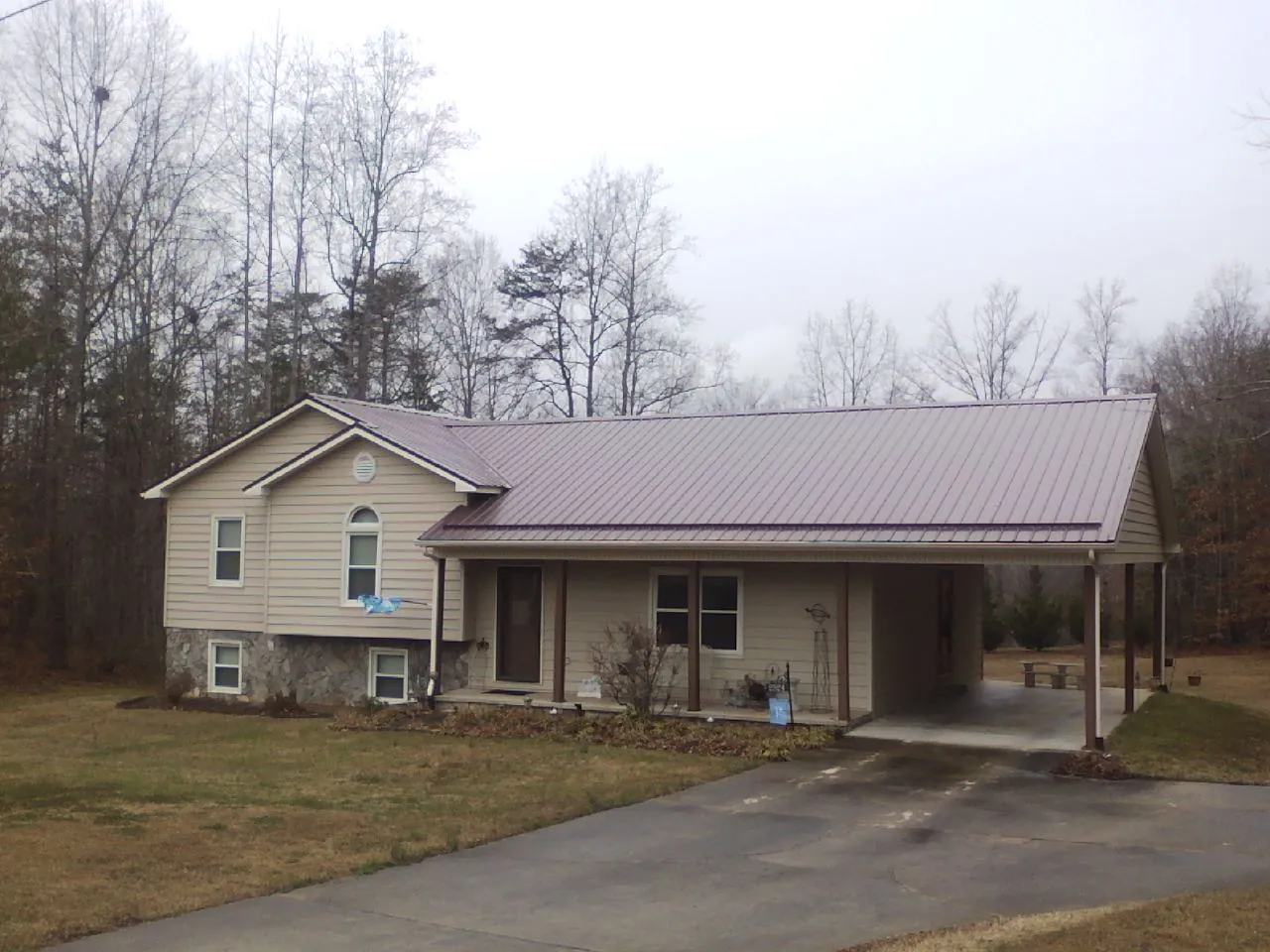 Burgundy metal roof on a tan split level home with an attached carport in Crooksville