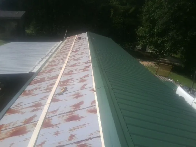 Old rusted panels beside newly installed green metal roofing — Wind Damage Roof Repair by Roofing Brothers in Crooksville