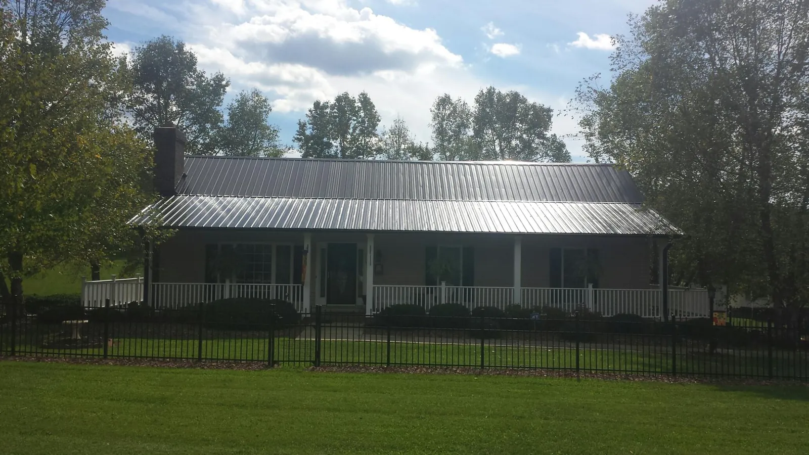 Gray metal roof on a brick ranch with a full width front porch — Gutter Guard Installation work by our crew in Crooksville