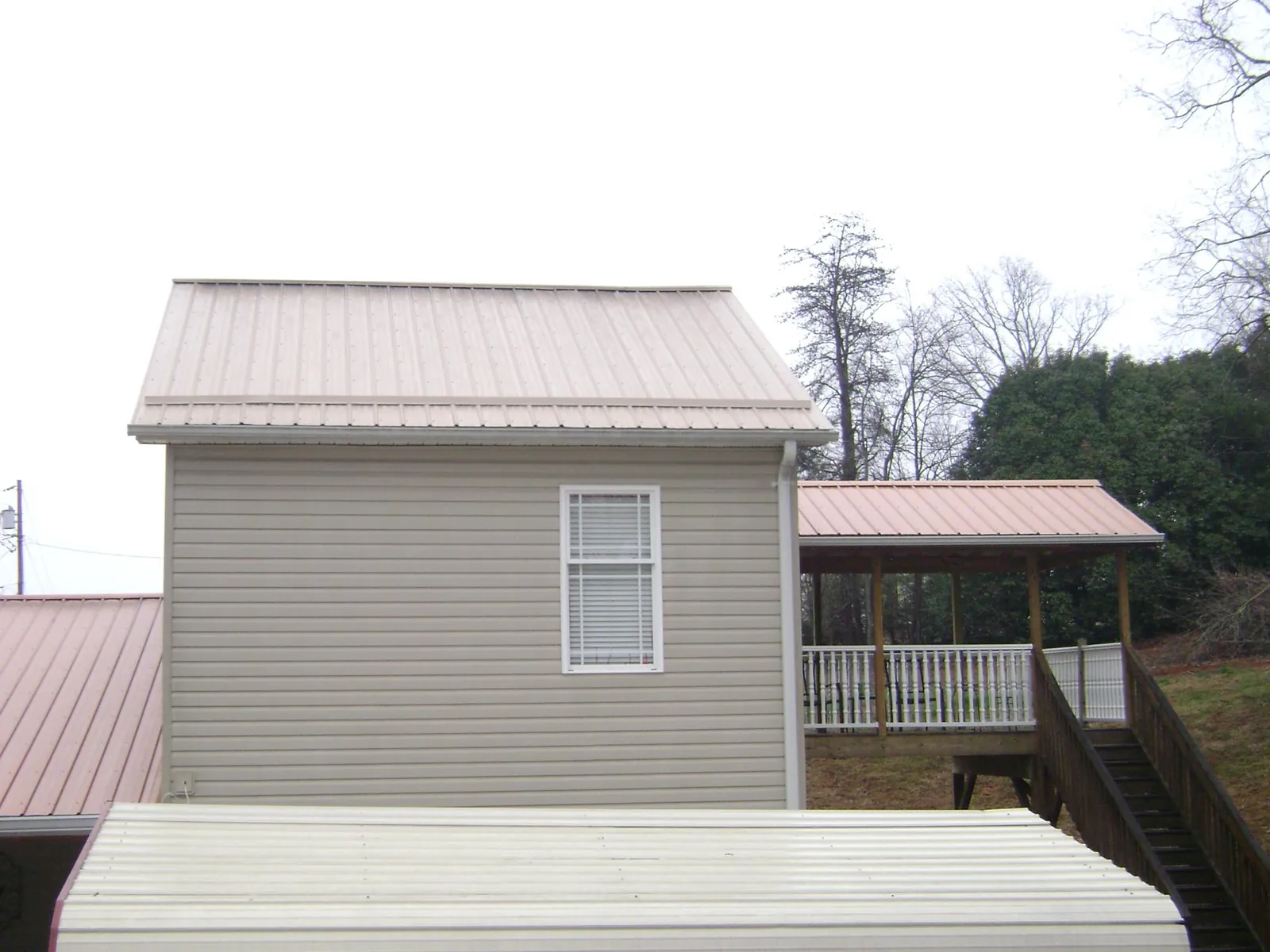 Tan metal roofs on a two story addition and attached porch, from a Roof Replacement job in Crooksville