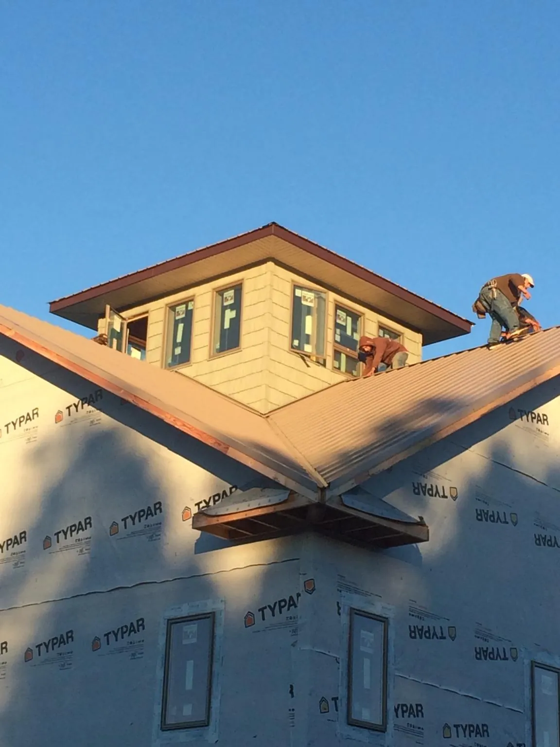 Roofers working around a rooftop cupola on a new metal roof at sunset — Roof Waterproofing in Crooksville by Roofing Brothers
